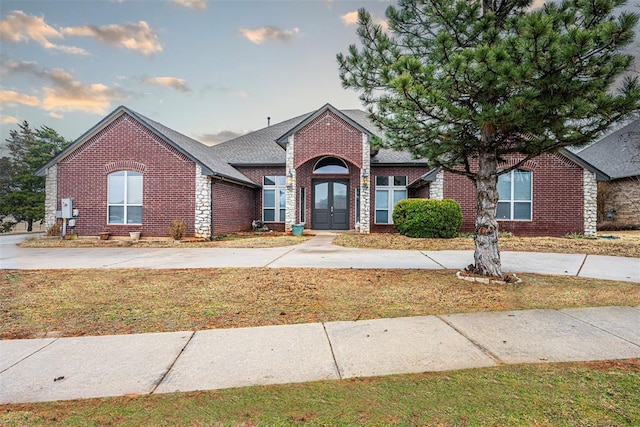 traditional-style house featuring a front yard, french doors, and brick siding