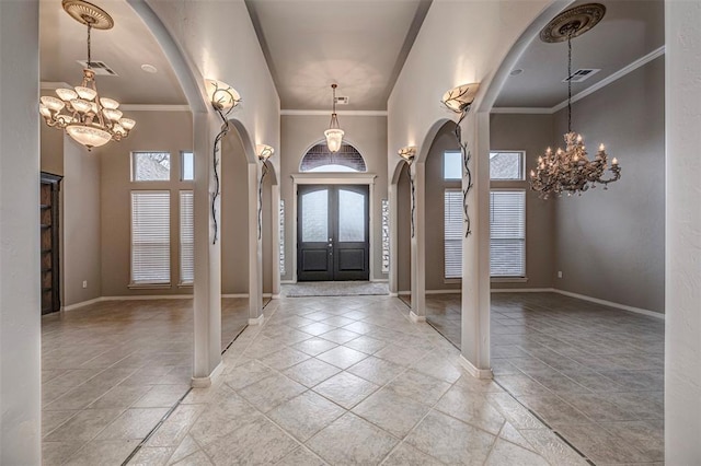 foyer featuring visible vents, arched walkways, a notable chandelier, and ornamental molding