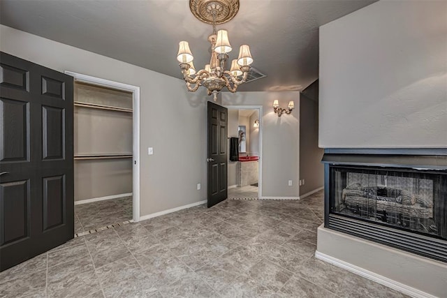 unfurnished living room with a chandelier and baseboards