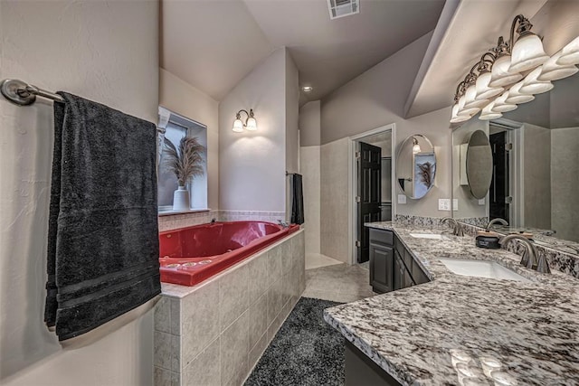 bathroom featuring double vanity, visible vents, a sink, and a bath