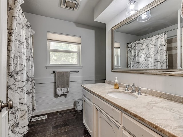 bathroom featuring visible vents, a wainscoted wall, wood finished floors, vanity, and wood walls