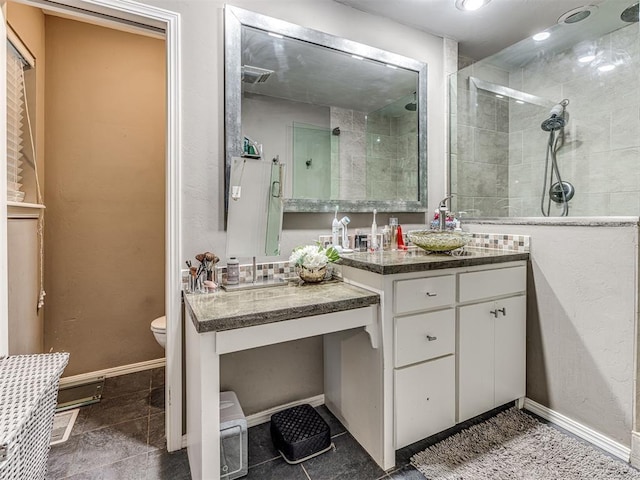 bathroom with toilet, a stall shower, vanity, baseboards, and tile patterned floors