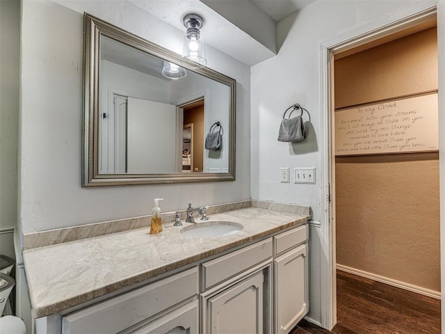 bathroom featuring a textured wall, wood finished floors, vanity, and baseboards