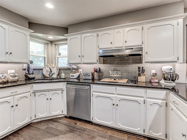 kitchen featuring tasteful backsplash, dark wood finished floors, dark stone counters, under cabinet range hood, and white cabinetry