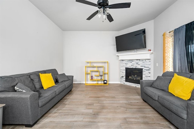 living room with a fireplace, wood finished floors, a ceiling fan, and baseboards