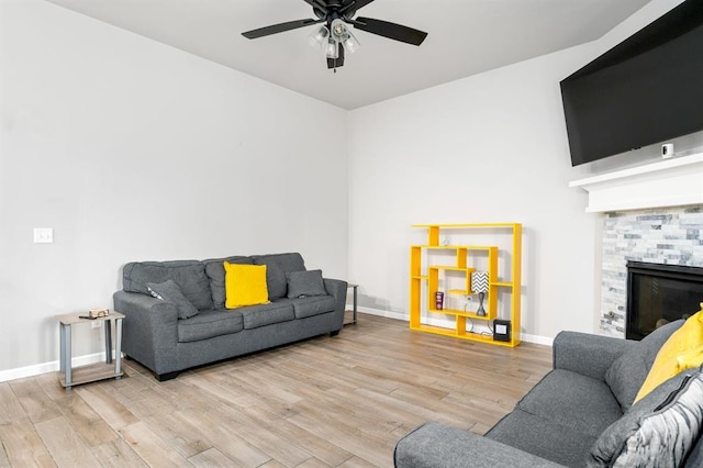 living area with ceiling fan, a fireplace, baseboards, and wood finished floors