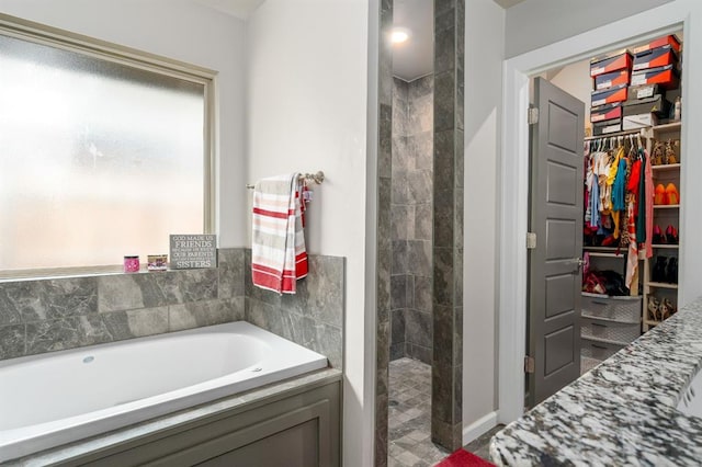 bathroom with a spacious closet, tiled shower, and a garden tub