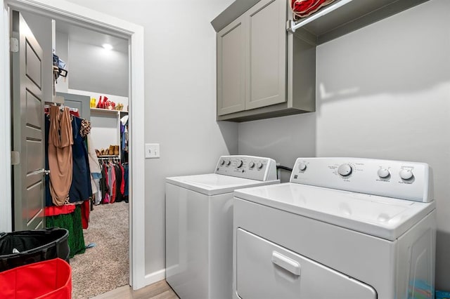 clothes washing area with washing machine and dryer, cabinet space, and light colored carpet