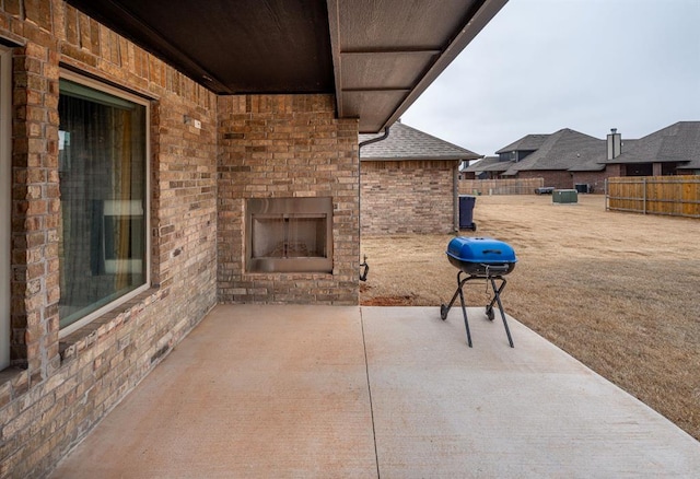 view of patio / terrace with an outdoor brick fireplace, fence, and area for grilling