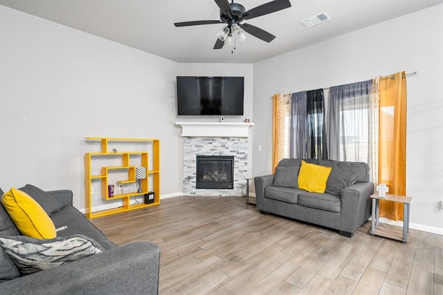 living area with baseboards, visible vents, a ceiling fan, wood finished floors, and a fireplace