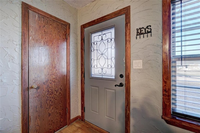 doorway to outside with light wood-style floors and a textured wall