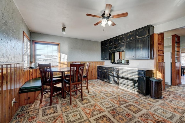 dining area with ceiling fan and a textured wall