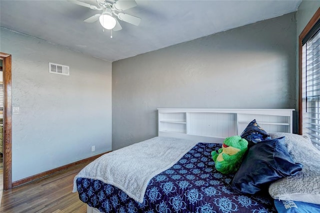 bedroom featuring a ceiling fan, baseboards, visible vents, and wood finished floors