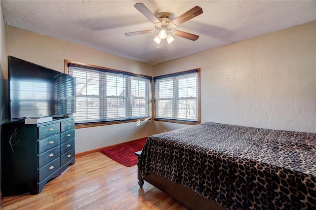 bedroom with a textured wall, ceiling fan, and light wood-style flooring