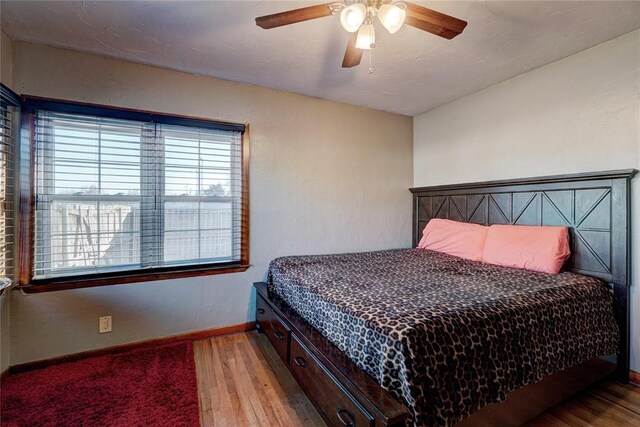 bedroom with ceiling fan, light wood-style flooring, and baseboards