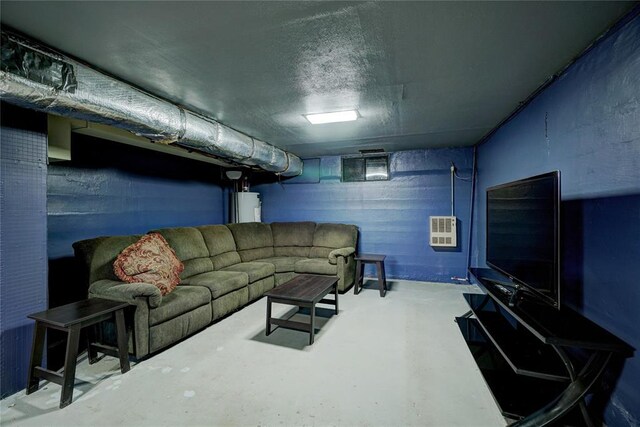 living area featuring heating unit, concrete floors, and electric water heater