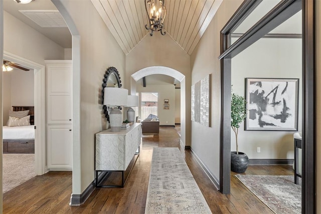 hallway with lofted ceiling, dark wood-style floors, and arched walkways