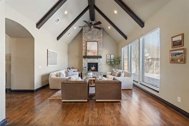 living area with visible vents, dark wood-style floors, beamed ceiling, a stone fireplace, and high vaulted ceiling