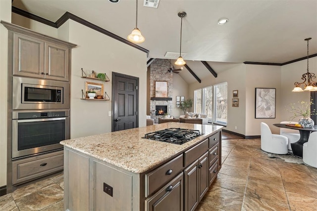 kitchen with ceiling fan with notable chandelier, stainless steel appliances, a fireplace, a kitchen island, and decorative light fixtures