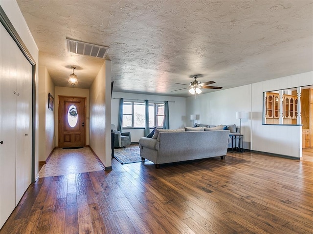 living room featuring visible vents, ceiling fan, a textured ceiling, and wood finished floors