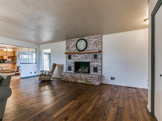 unfurnished living room featuring a textured ceiling, a fireplace, and dark wood-style flooring