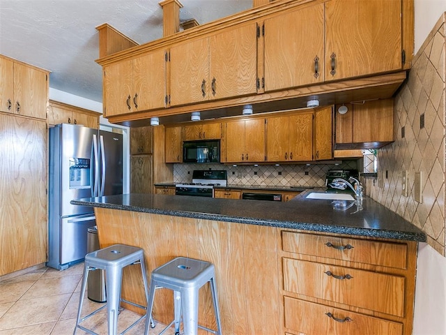 kitchen featuring dark countertops, black appliances, brown cabinets, and a sink