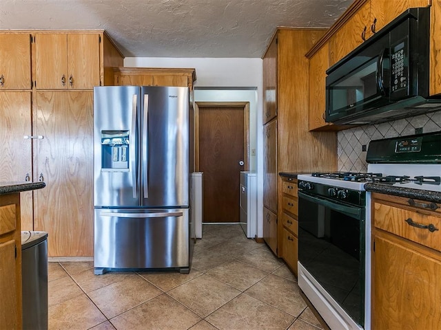 kitchen featuring dark countertops, a textured ceiling, black appliances, washing machine and dryer, and backsplash