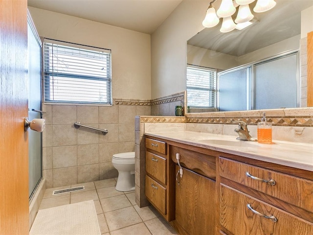 full bathroom featuring tile patterned flooring, vanity, tile walls, visible vents, and a shower with door