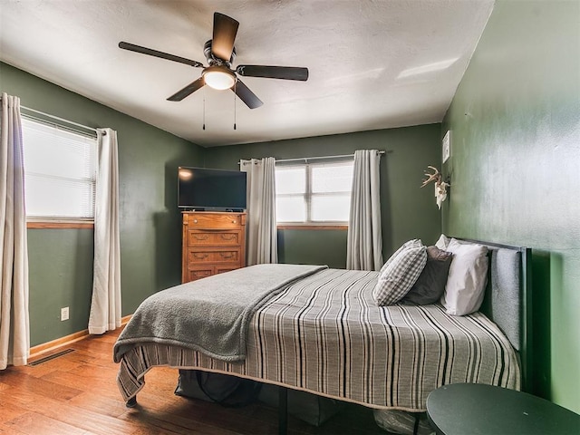 bedroom with light wood-type flooring, visible vents, ceiling fan, and baseboards