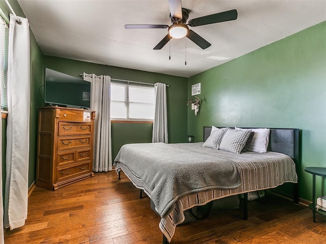 bedroom featuring ceiling fan, baseboards, and wood finished floors