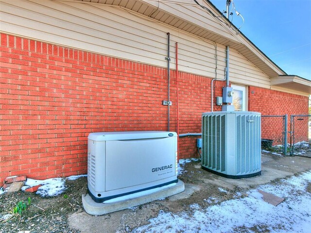 details featuring brick siding, fence, cooling unit, electric meter, and a power unit