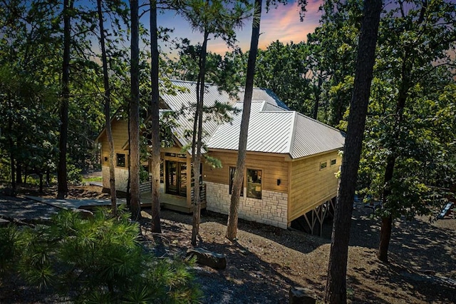 view of side of home with stone siding and metal roof