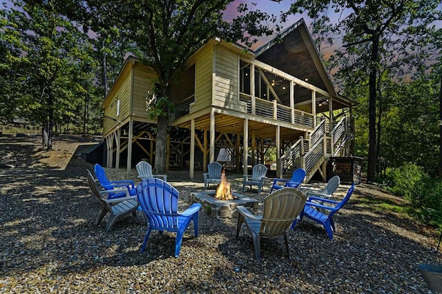 back of property at dusk with an outdoor fire pit and stairway