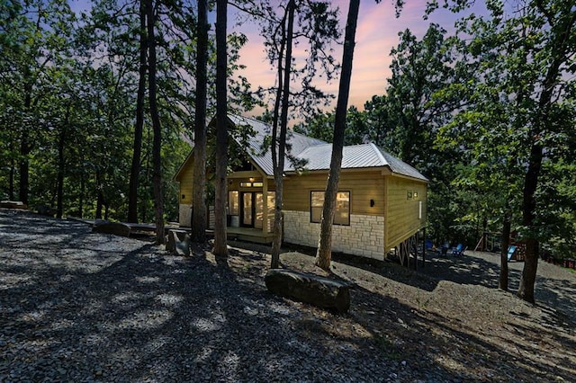 property exterior at dusk featuring metal roof and stone siding