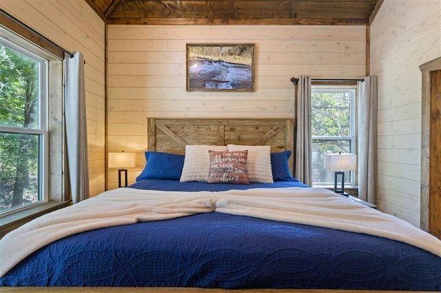 bedroom with lofted ceiling, wooden walls, and multiple windows