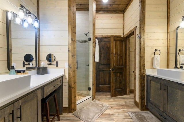 bathroom featuring a stall shower, wood finished floors, vanity, and wooden walls