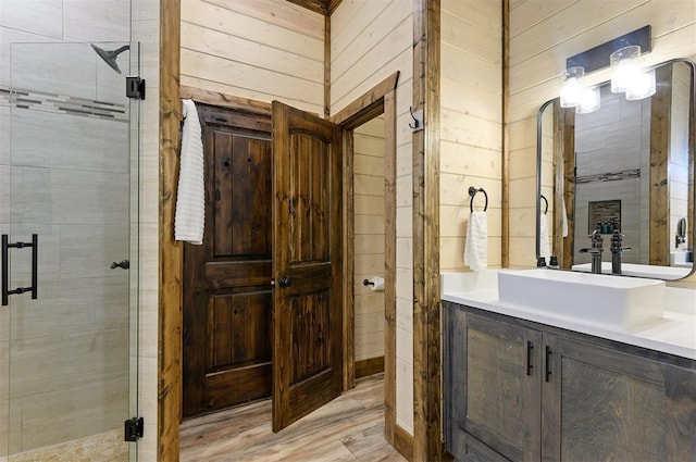 full bath featuring a stall shower, wooden walls, vanity, and wood finished floors