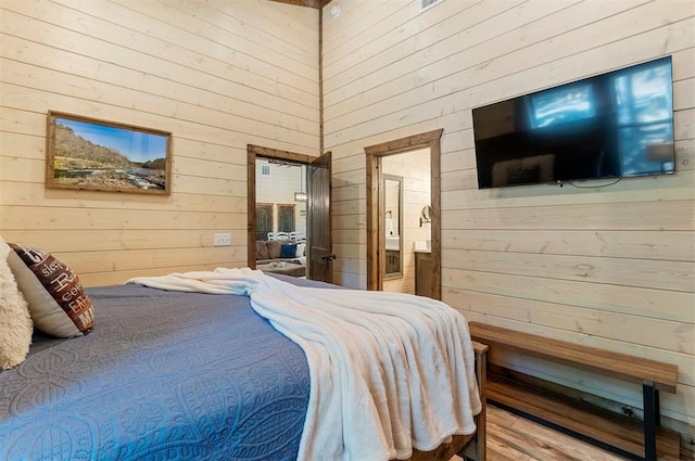 bedroom featuring wooden walls and ensuite bath