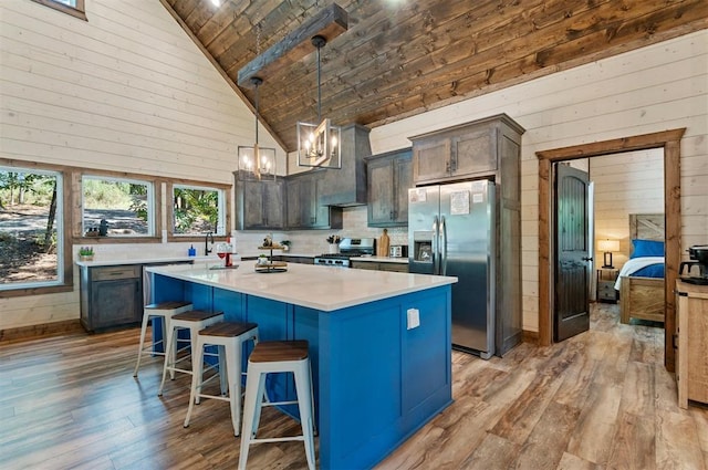 kitchen featuring appliances with stainless steel finishes, a breakfast bar area, a center island, light countertops, and pendant lighting