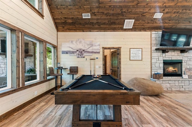 recreation room with wood walls, a fireplace, wood finished floors, visible vents, and vaulted ceiling