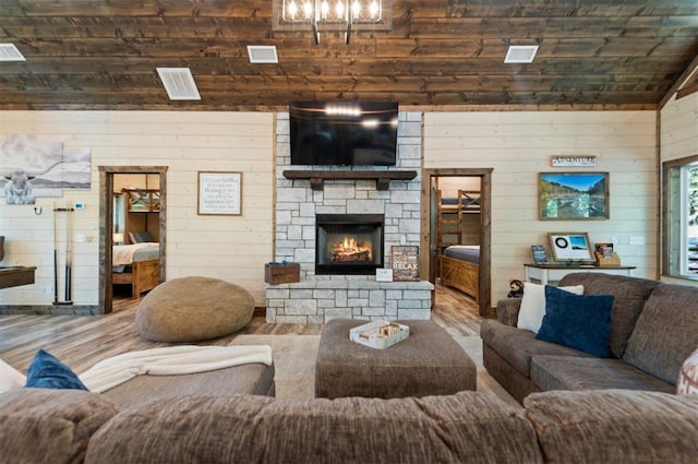 living area with lofted ceiling, a fireplace, wood finished floors, and visible vents