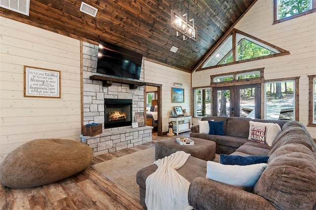 living area with wooden ceiling, wood walls, visible vents, and wood finished floors