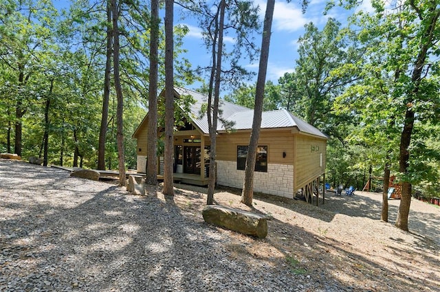 exterior space featuring stone siding and metal roof