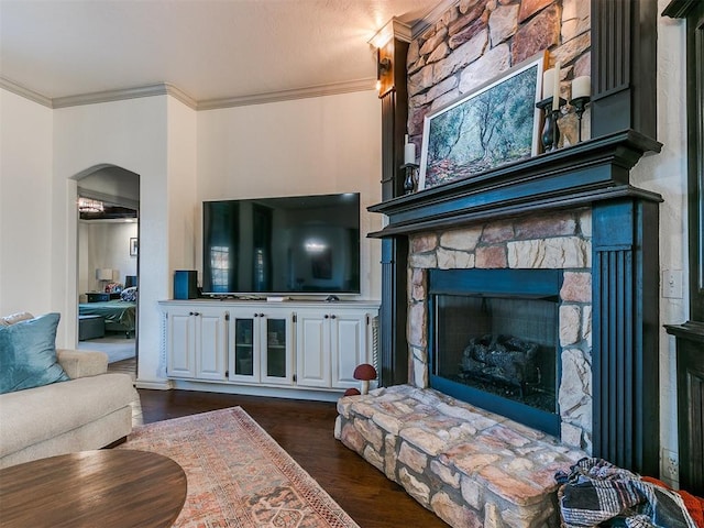 living room featuring ornamental molding, arched walkways, a stone fireplace, and dark wood-style floors