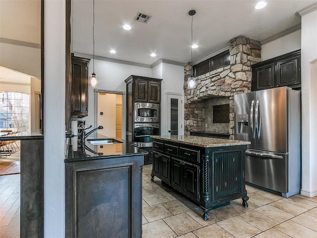 kitchen with a sink, visible vents, hanging light fixtures, a center island, and stainless steel fridge