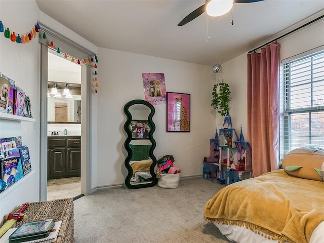 bedroom featuring light carpet, ceiling fan, baseboards, and ensuite bathroom