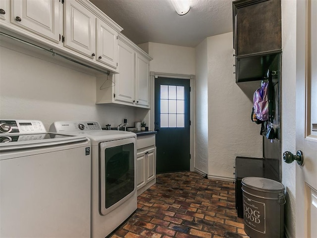 washroom with brick floor, cabinet space, a textured wall, a textured ceiling, and independent washer and dryer