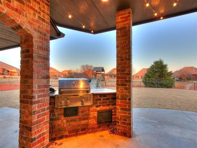 view of patio with exterior kitchen, a grill, fence, and a playground