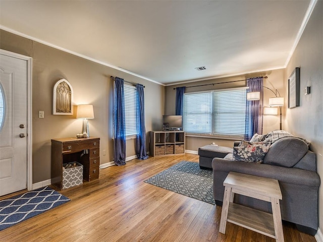 living area with baseboards, crown molding, visible vents, and wood finished floors