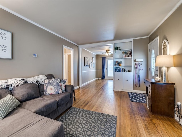 living area featuring baseboards, wood finished floors, and crown molding